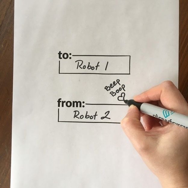 A hand filling in the blanks on a piece of paper labeled with the words too and from