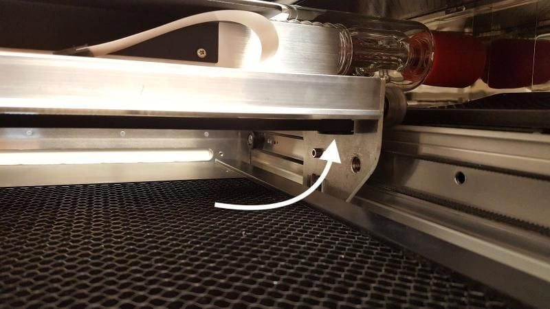 An arrow pointing to the idler pulley under the right side of the laser arm