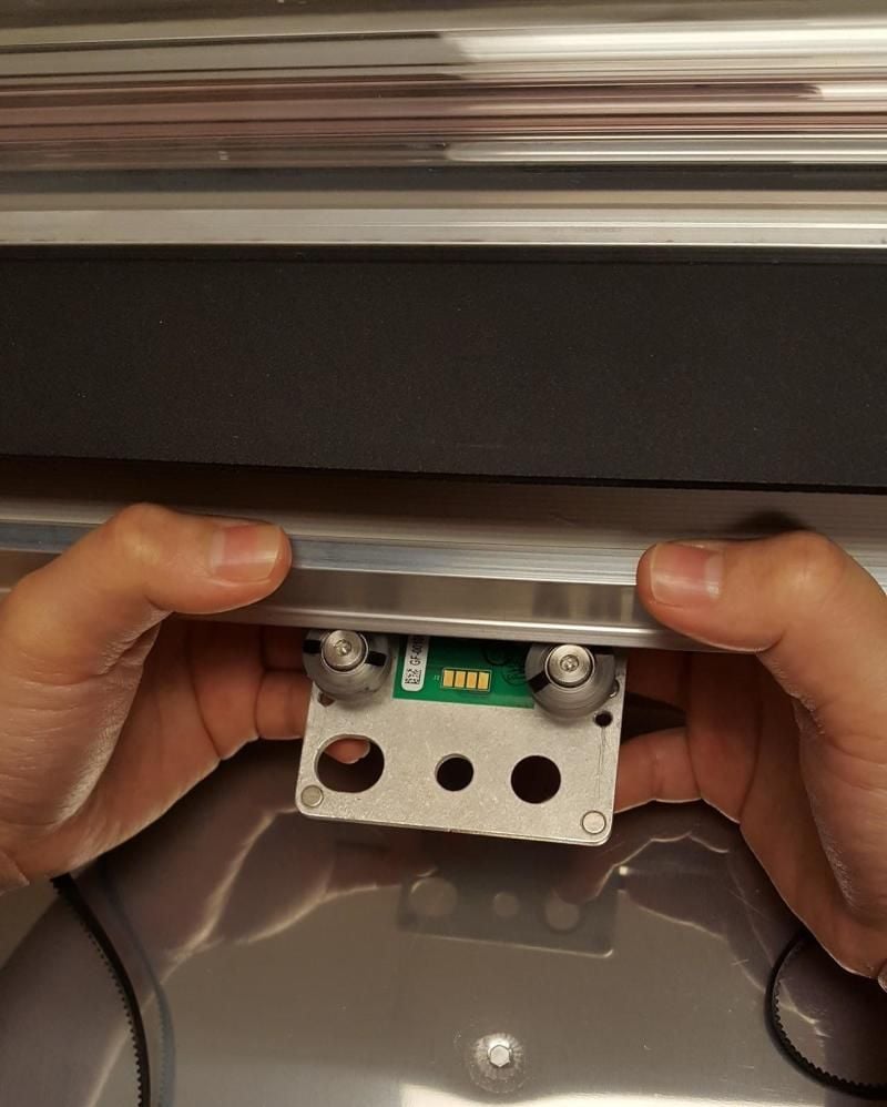 The carriage plate being held under the laser arm, with its back wheels hooked behind the back side of the laser arm.