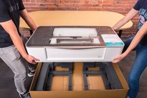 two people lifting a Glowforge