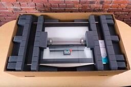 A Glowforge in its shipping box with protective foam both under it and on top of it