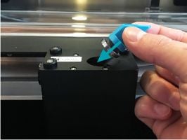 Fingers grasping the two large, flat sides of the mirror handle. The mirror is pointed towards the inside of the print head.
