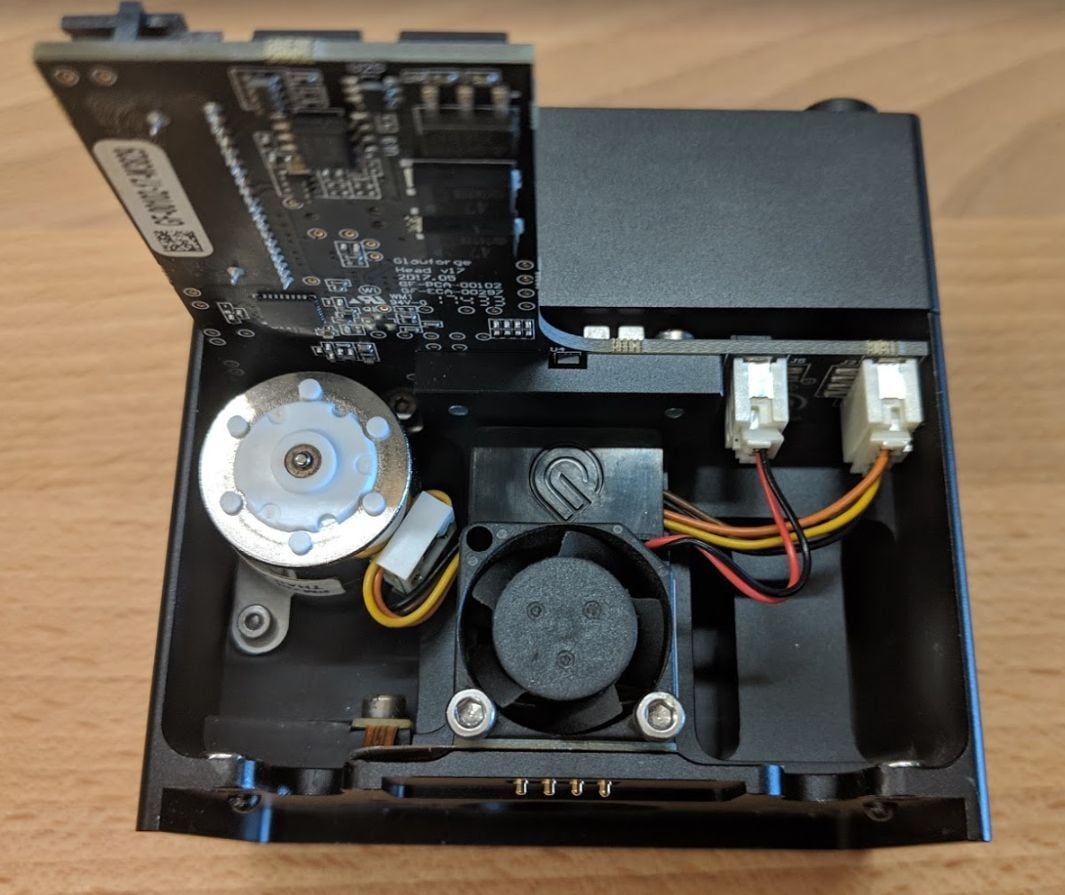 Image of the back of the Glowforge print head. The back of the head has an exposed motor, circuit board and small fan.