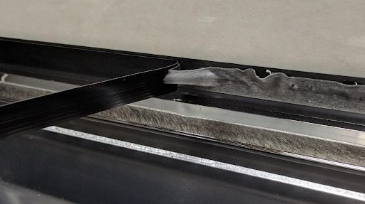 A cable being peeled off of the Glowforge lid interior