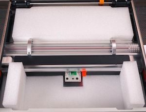 A Glowforge with its lid open and both the front and back protective foam blocks inserted into the bed.