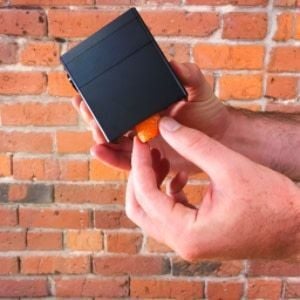 A hand grasping an orange foam cylinder sticking out of a Glowforge print head