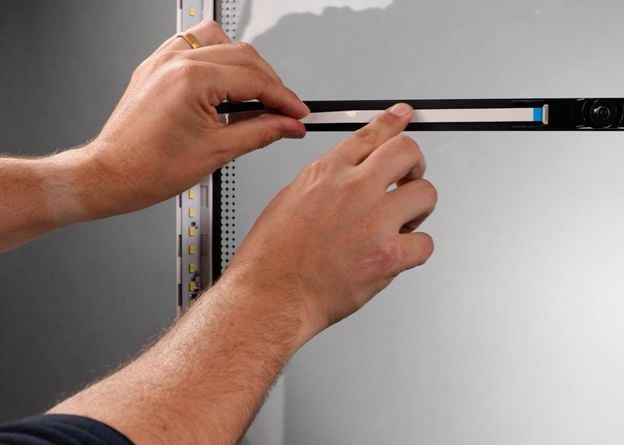 One hand holding the cable, the other pressing on it to stick the adhesive backing down