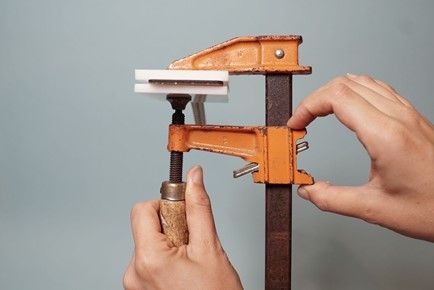 A vice clamped down on a blank leather luggage tag sandwiched between a lasercut stamp and a blank piece of acrylic