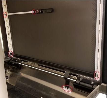 A Glowforge with its lid open. The 3 connections on the black lid cable near its hinge and the 2 connections on the white lid cable leading to the camera are circled.