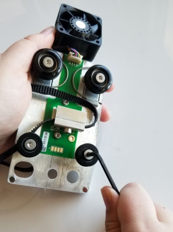 One hand holding the carriage plate, the other holding a 3mm hex key inserted into a front wheel screw