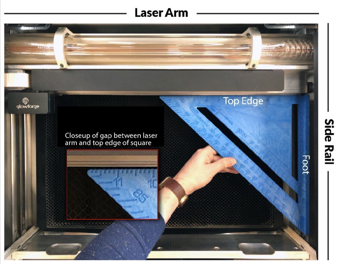 Glowforge with the lid open and arm pushed all the way back. A hand holds a carpentry square against the arm and frame
