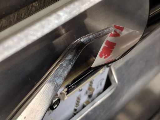Tweezers removing the covering from the cable's adhesive backing