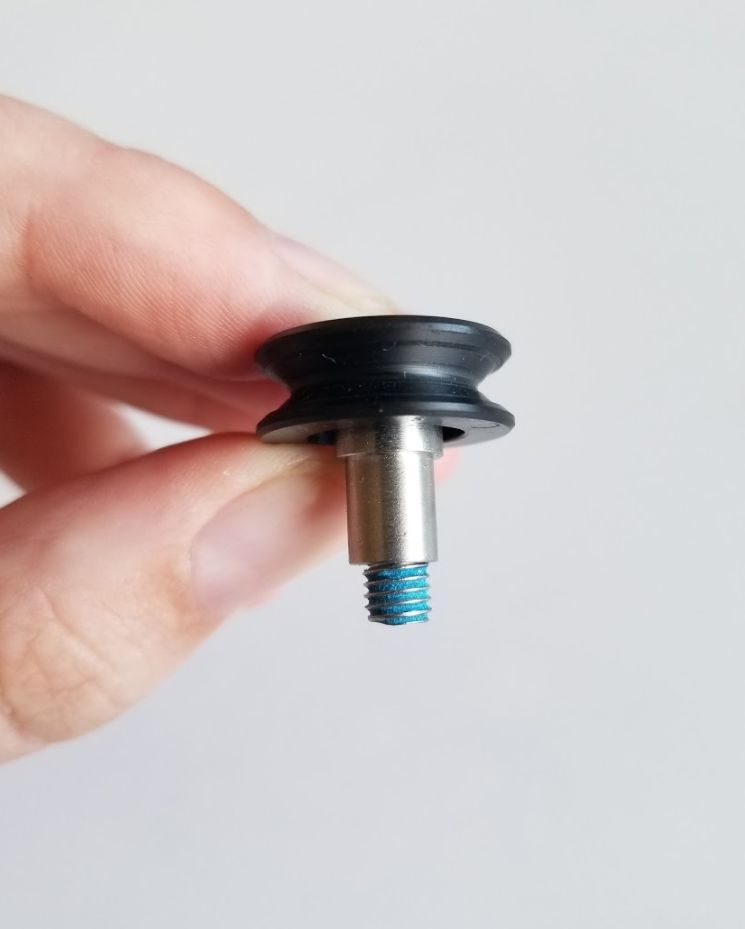 A front carriage plate v-wheel with a screw inserted through the hole & a spacer over the other side of the screw