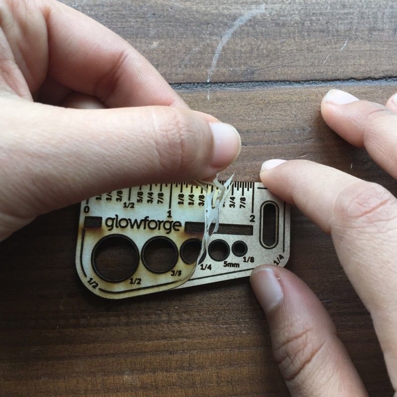 Close-up of hands peeling the masking off a completed Gift of Good Measure keychain