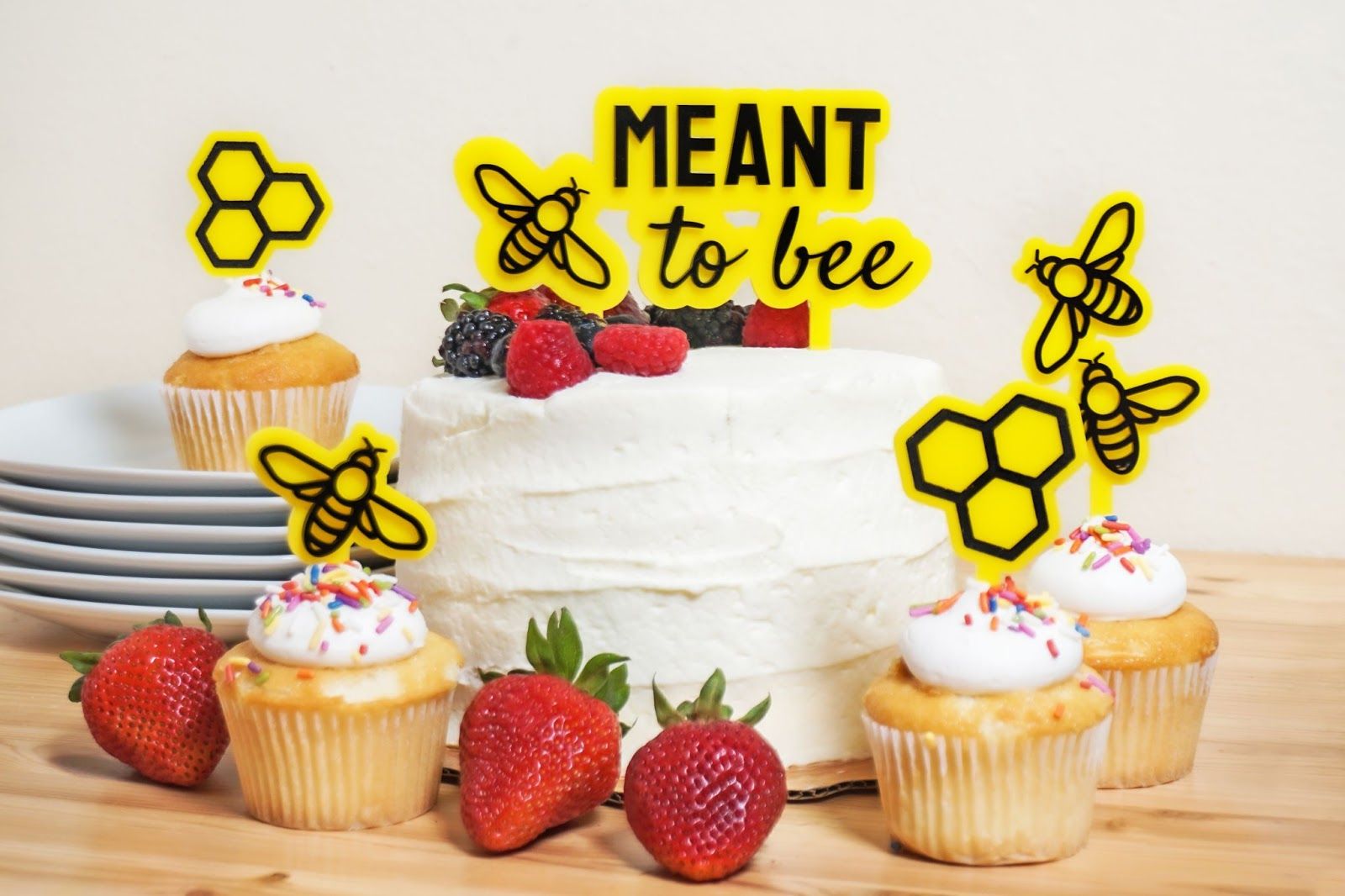 Completed, laser cut cake toppers with a bee theme in cupcakes and a large cake